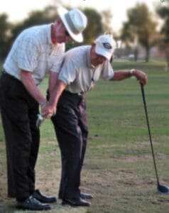 Manuel de la Torre guiding a student's grip during a golf lesson
